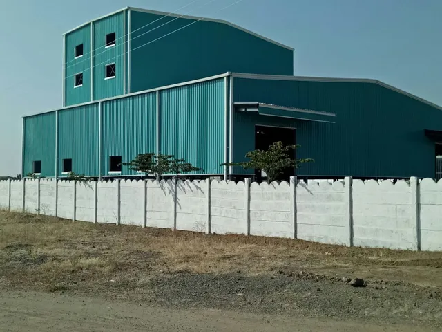 Completed teal factory building with multi-level PEB construction and compound wall