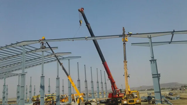 Cranes erecting the steel portal frames of a large-span PEB building