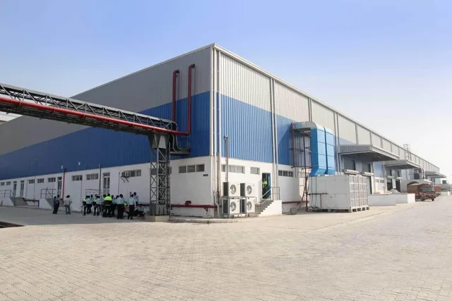 Large blue and white industrial manufacturing facility with paved surroundings
