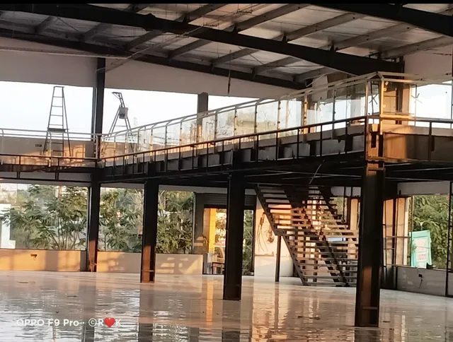 Commercial building interior with steel mezzanine floor, staircase and glass railing