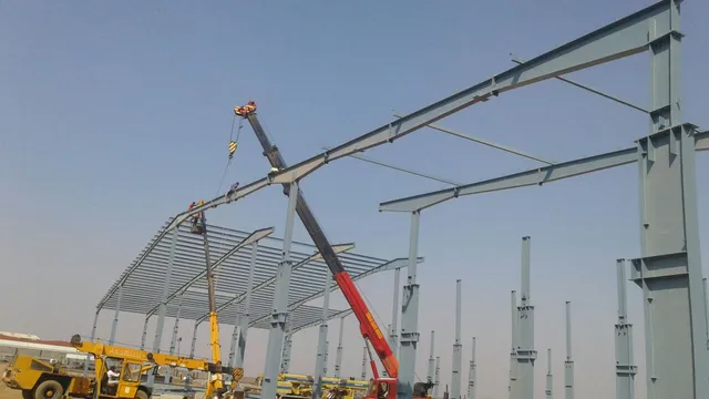 Mobile crane lifting steel members during industrial structure erection