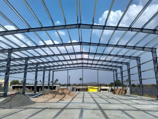 Steel portal frame of a PEB shed erected against a clear blue sky